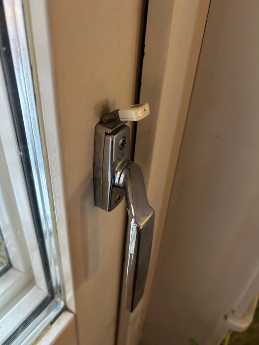 Balkongdörrhandtag med barnspärr installerad ovanför handtaget.