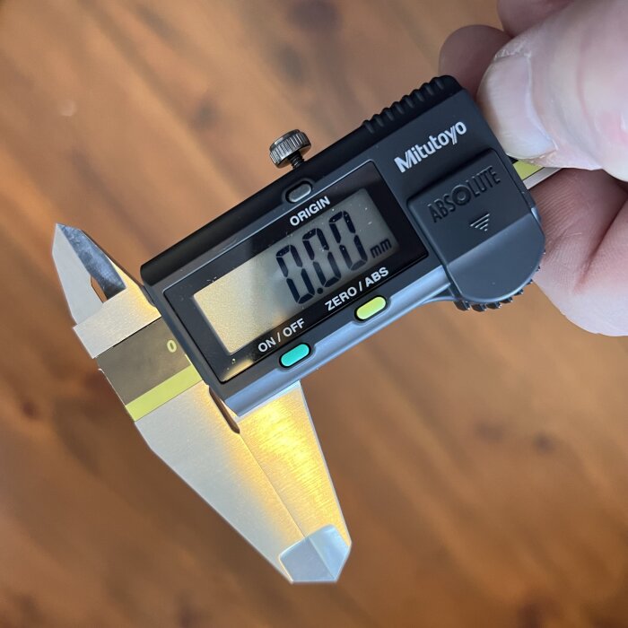 Digitalt skjutmått med display som visar 0.00 mm, hålls i en hand och används för precisionsmätning.