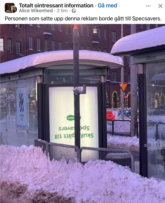Reklamskylt för Specsavers uppsatt upp och ner i en snöig busskur.