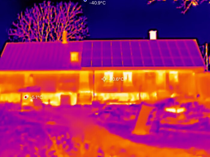 Termisk bild av ett hus sett på avstånd, visar temperaturskillnader i fasaden och solceller på taket. Temperaturer markeras på bilden.