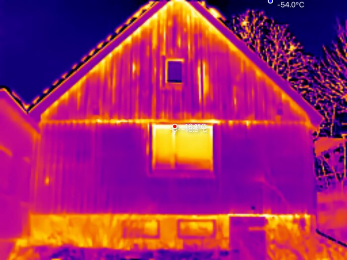 Termisk bild av husfasad i mörka färger som visar värmeläckor. Temperaturen är markerad som -10,1°C. Fotad med lågupplöst kamera.