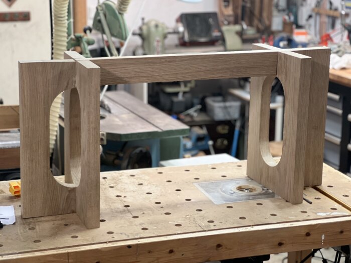 Träram står på en arbetsbänk i verkstadsmiljö, del av ett soffbord eller bänkprojekt, med fokus på konstruktion och design.