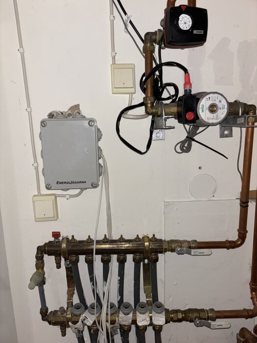 VVS-installation med rör, ventiler och pumpar på en vägg.