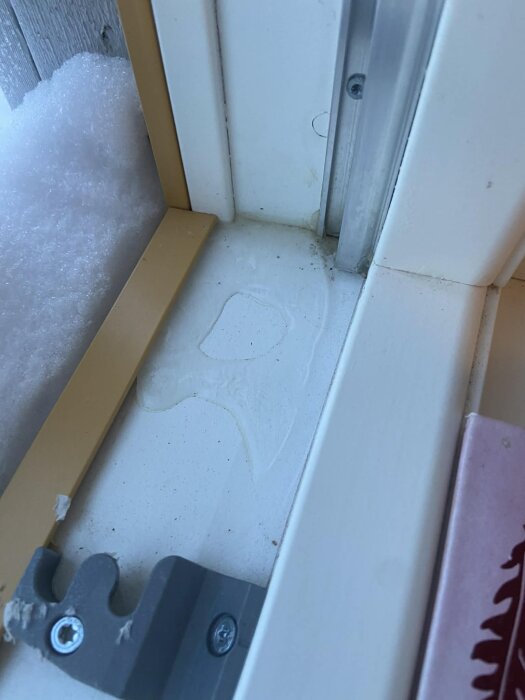 Kondens på insidan av ett fönster i ett nyproducerat hus med snö utanför, visar tecken på fuktproblem vid fönstrets nedre del.