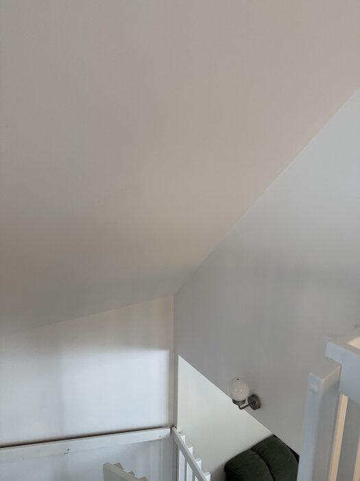 Ett vitt trapphörn med en vägglampa, där det drar kall luft in. Eventuell placering för isolering övervägs.