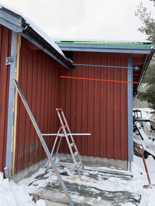 Garagets utbyggnad med snötäckt tak, röda väggar och blå linjer för olika takförslag. Stege och verktyg syns på marken i snön.