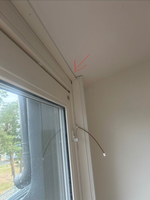 Bilden visar ett snedtak i ett rum, med en list längs taket som hindrar gardininstallation. En kabel löper ned från taket vid ett fönster.