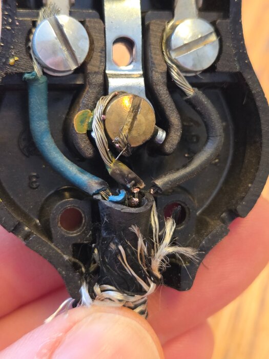 Öppen elektrisk kontakt med ledningar och skruvar, visar tidigare problem och reparation.