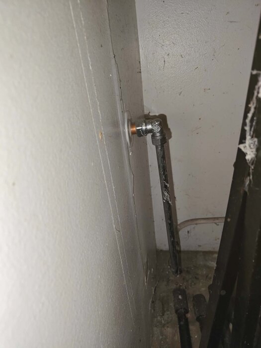 Rör och ventil mellan bergvärmesystem och vägg i ett hus.
