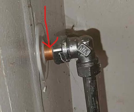 Kopparrör instucket i vägganslutning med synlig mutter och röd markering som indikerar möjlig glidning.