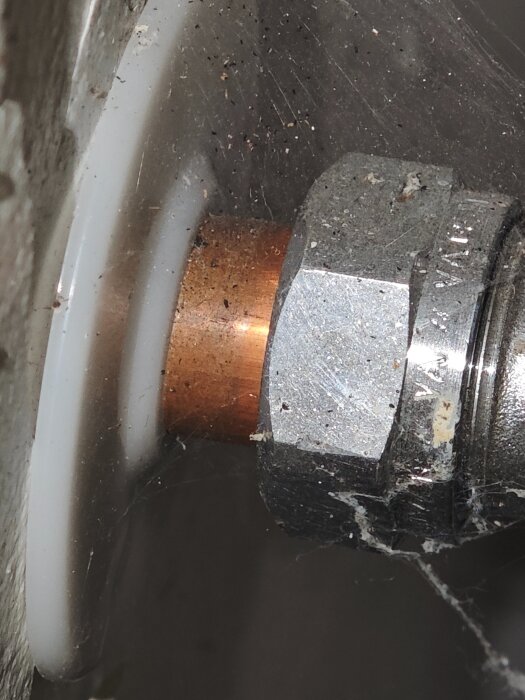 Närbild på ett metallrör med gängad koppling och smuts ackumulerad på ytan.