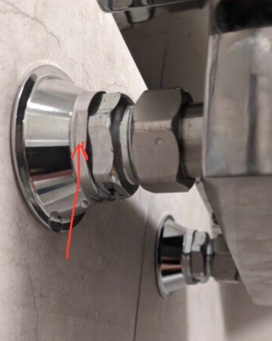 Kromfärgat blandarfäste med markerad mutterdel, installerat på en vägg; diskuteras om täckkåpor av borstad nickel täcker mutterdelen.