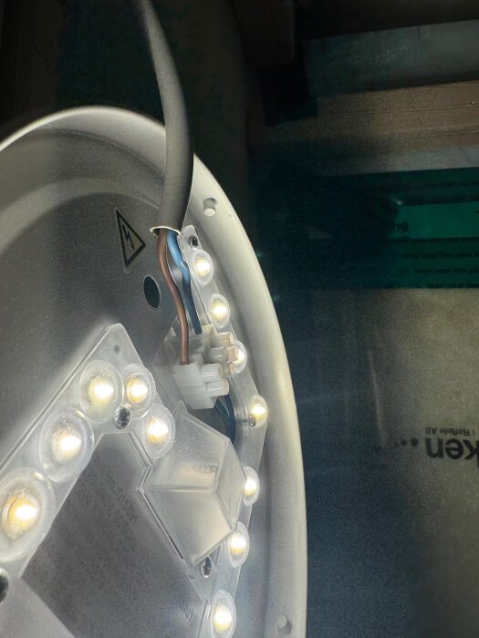 Närbild av en taklampa med LED-lampor och synliga elkablar kopplade i lamphållaren.
