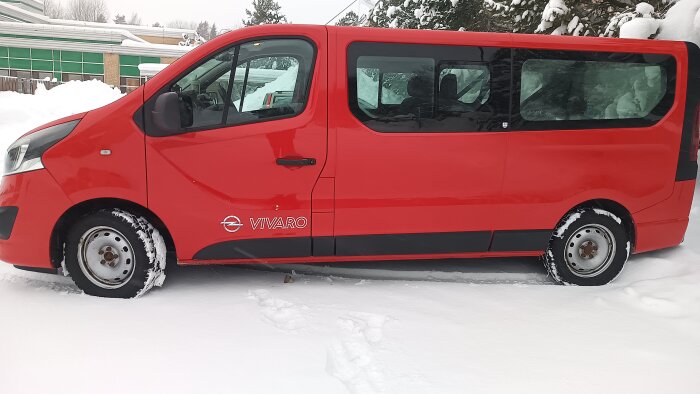 Röd Opel Vivaro parkerad i snön efter en tur genom biltvätten, i ett vinterlandskap med snö och träd i bakgrunden.