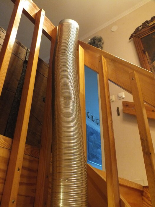 Korrugerad aluminiumrör installeras längs en trappa, inuti ett trästaket, för att leda värme mellan våningsplan.