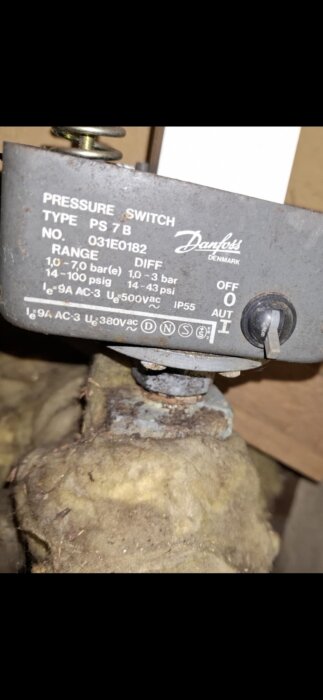 Tryckströmbrytare av märket Danfoss, modell PS 7 B, monterad på en del av en hydrofortank med synlig rost.