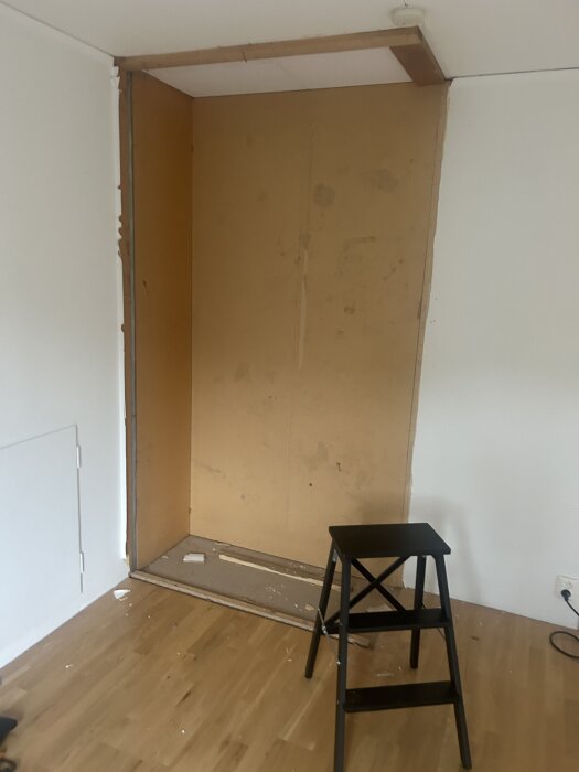Åbent skab uden døre under renovering, glip i væg og loft synlig. Sort skammel på gulvet ved siden af skabet.