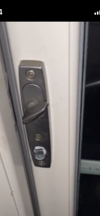 Altandörr med trasigt handtag och en synlig skruvplatta, del av en diskussion om att byta till nytt handtag och passa hålen i dörren.