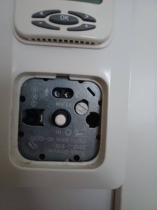 Väggmonterad dimmer utan frontplatta och lampdel, knappar ovanför.