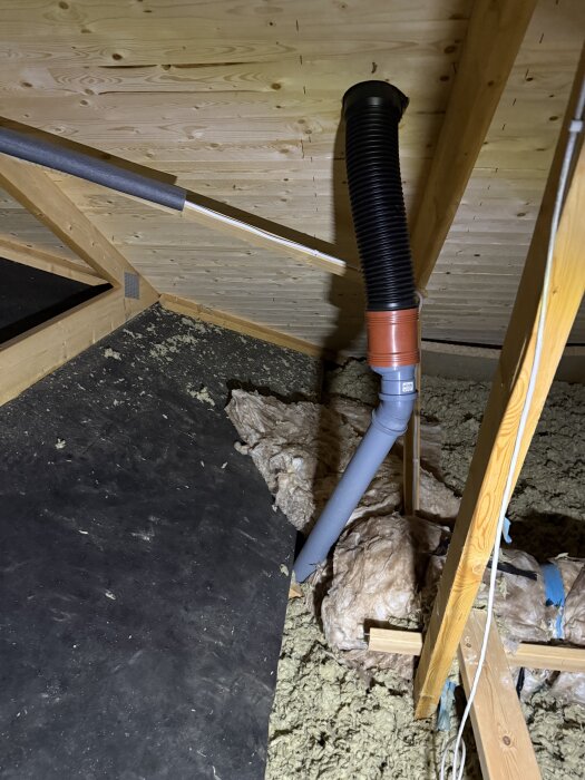 Avloppsluftningsrör genom tak med isolering och fuktmarkeringar i ett vindsutrymme.