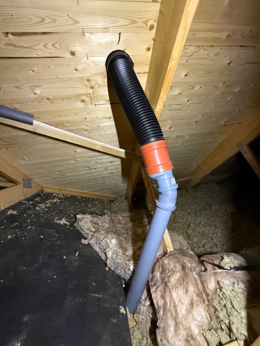 Avloppsluftningsrör genom tak med isolering runt, synlig läckagepunkt; ullisolering och träpanel i bakgrunden.