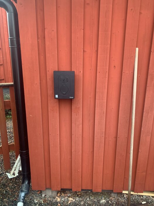 Laddbox Zaptec Go monterad på en orange trävägg, bredvid ett svart stuprör.