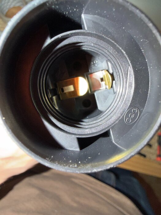 Närbild av insidan av en lamphållare med metallkontakter synliga på båda sidor.