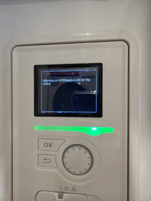 Nära bild på en vit kontrollpanel med en display som visar meddelandet: "Kalibrering av luftflödesgivare BS1 är inte utförd.