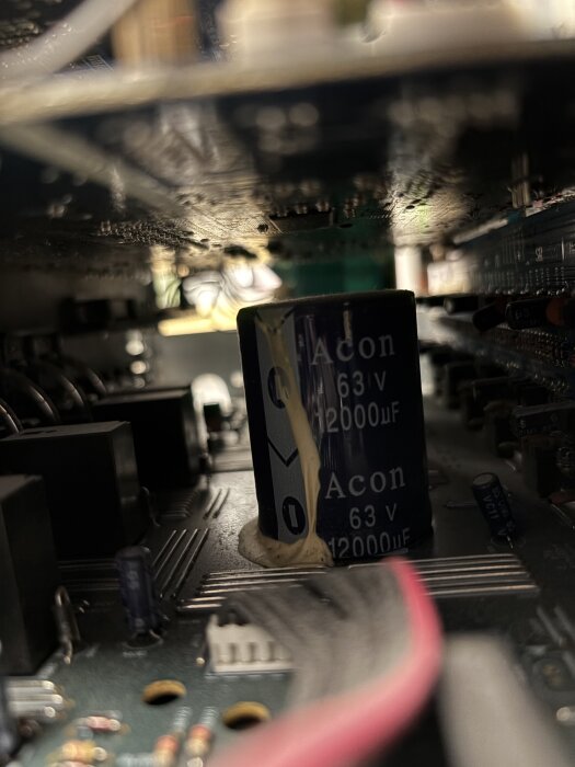 En närbild av ett kretskort med tydligt synliga elektrolytkondensatorer märkta "Acon 63V 12000uF", omgivna av flera elektroniska komponenter.