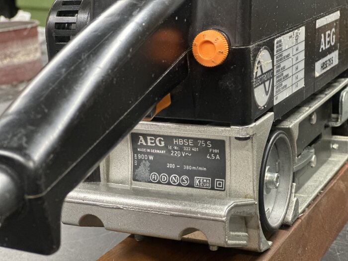 AEG bandslip HBSE 75 S med orange hastighetsvred, etiketter och detaljer synliga, inställd på arbetsbänk.