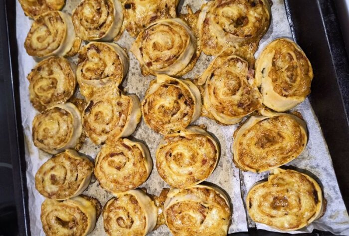Hemlagade pizzabullar med kryddad tomatsås på en bakplåt.