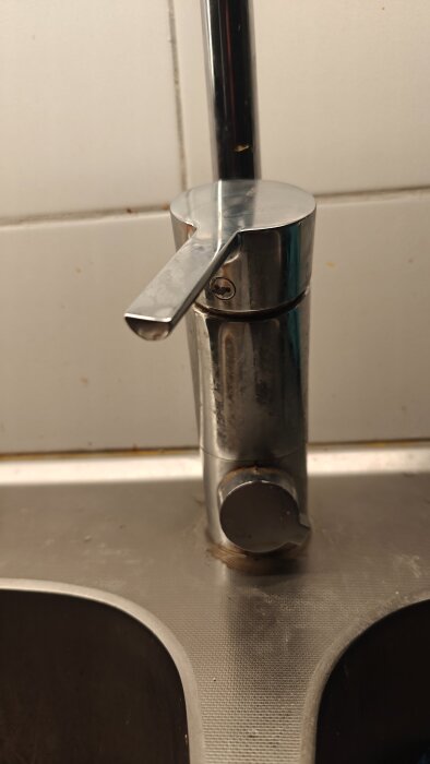 Köksblandare med kromfinish, morakran, med en lysande ventil och en läckande pip på en diskbänk.