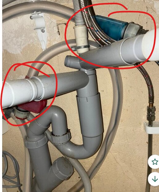 Två aquastop-enheter under diskbänken kopplade till avloppsrör och vattenledning, omgivna av plast- och metallrör.