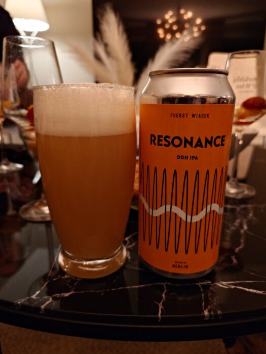 En burk Resonance DDH IPA från Fuerst Wiacek bredvid ett glas med öl på ett bord.