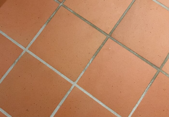 Klinkergolv med mörkare fogar, ett område är ljusare efter ångrengöring.