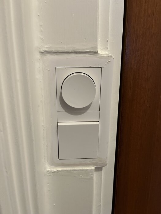 Vit vriddimmer installerad i en vit vägg med träram intill, där ramarna är "inspacklade", diskussion om ljudnivå vid användning.