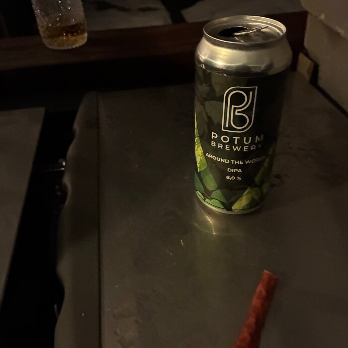 Ölburk med etikett "Potum Brewery, Around the World, DIPA, 8,0%" står på mörkt bord.