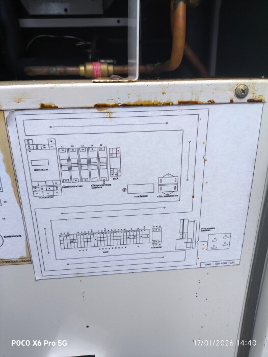 Ritning av elektrisk panel och kopplingsschema på en vägg, synlig rost och rör samt en kontaktor.