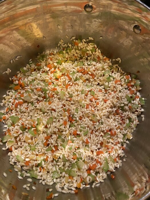 Risottoris med hackade grönsaker såsom selleri och paprika i en kastrull.
