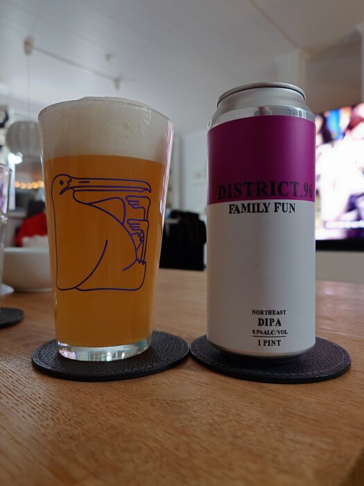 Ölglas med skummande öl och en burk märkt "District 96 Family Fun" på ett trädgårdsbord inomhus.