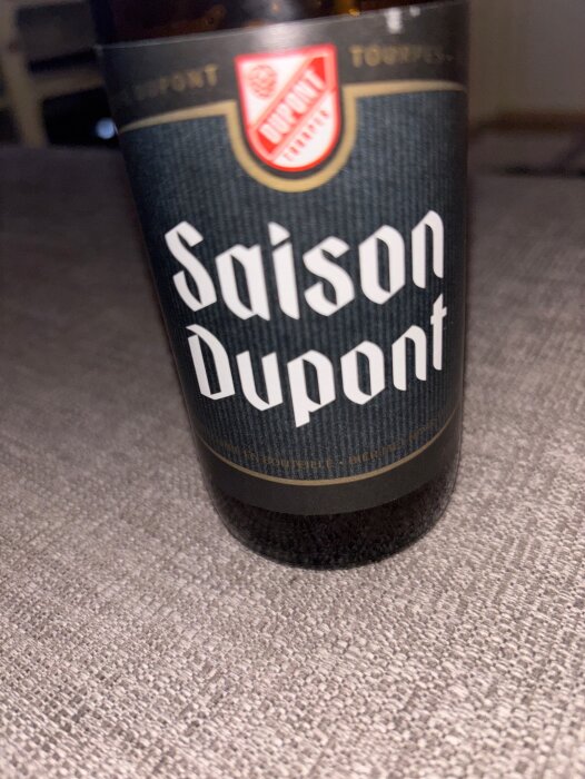 Flaska med Saison Dupont-öl på ett bord, del av ett uppskattat utbyte.