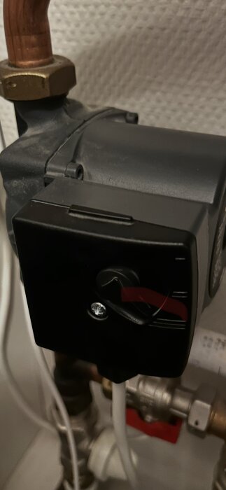 Cirkulationspump, Grundfos UPS 15-40, med reglage, omgiven av rör och kopplingar, monterad på vägg.