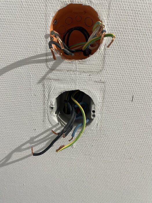Elektriska ledningar sticker ut från två öppna dosa i en vägg efter att apparaten tagits bort.