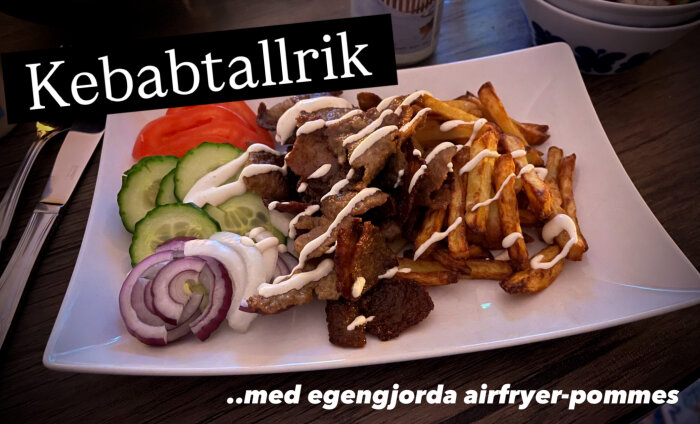 Kebabtallrik med kött, airfryer-pommes, gurka, tomat, rödlök och vit sås på en fyrkantig tallrik.
