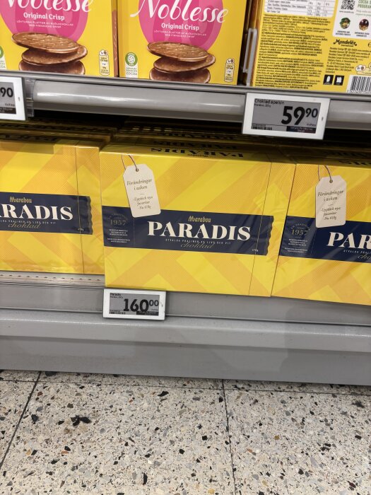 Paradis-askar på hylla i livsmedelsbutik med reapris 160 kr, Noblesse-kakor i bakgrunden.