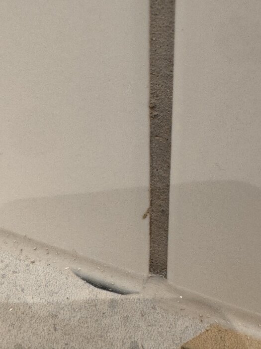 Närbild av kakel med ojämna och trasiga kanter, samt bred fog med slarvig applicering.