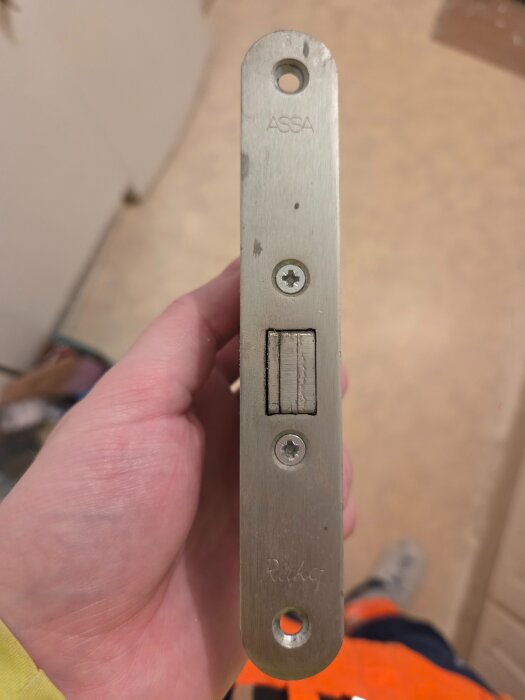 ASSA dörrlås, modell Fas 309, hålls i handen, synlig framsida med skruvar och märkning.