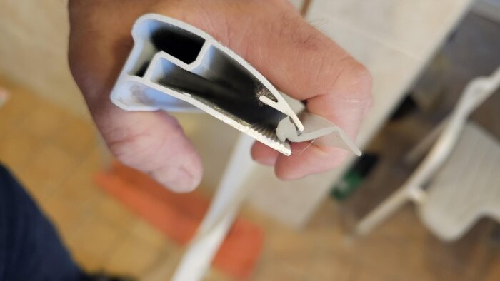 Hand som håller en aluminiumskena med ett felaktigt insatt gummi.