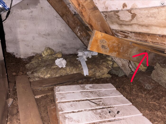 Bild på en vind med isolering synlig vid ett ventilationsrör. En röd pil markerar området med värmeläckage.