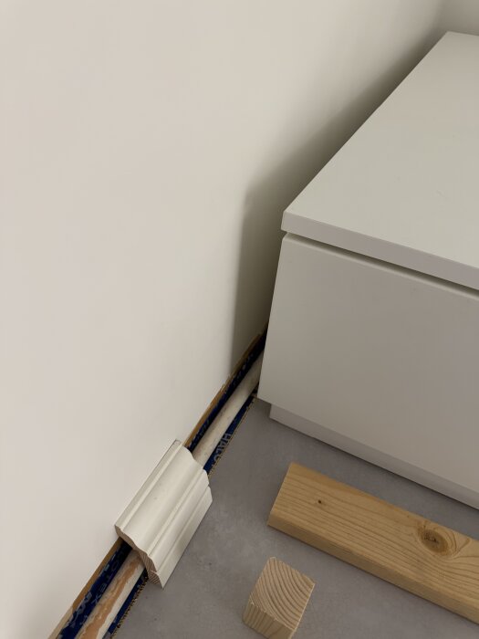 DIY golvlistinstallation med en svanhalslist och ventilerad golvsockel vid ett vitt skåp i ett barnrum.